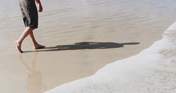 Mand der går på stranden